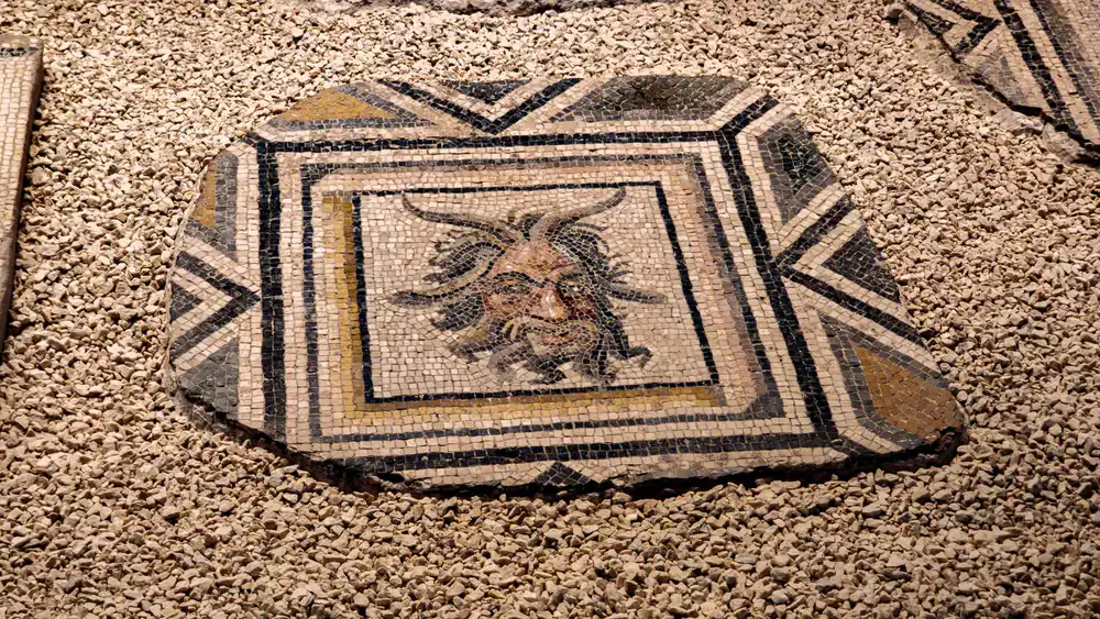Conservator resetting loose stone tesserae on a floor pavement